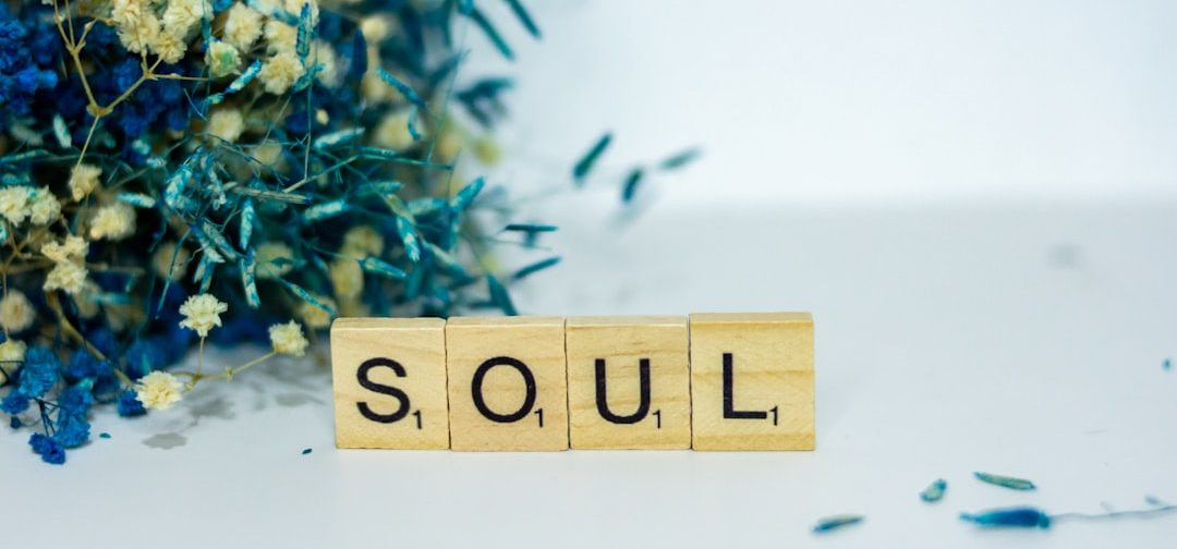 a wooden block spelling the word soul next to a bouquet of flowers