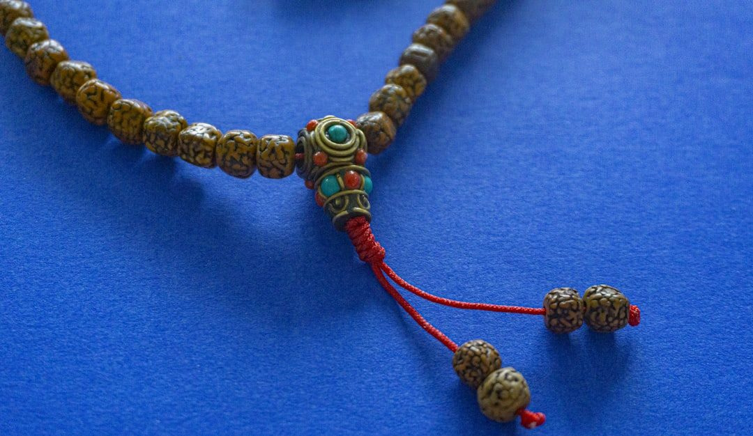 a close up of a beaded necklace on a blue surface