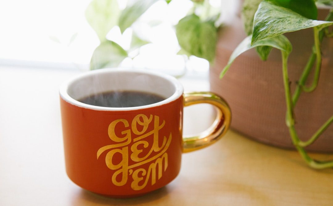 orange and white ceramic mug near green leaf plant with brown potted