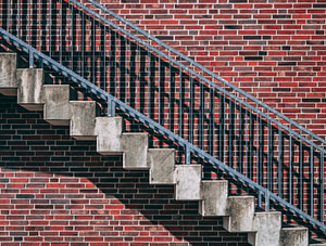 gray metal stair beside red brick wall