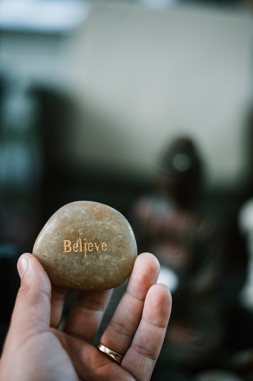 person holding brown stone with believe print