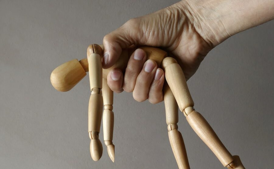 person holding brown wooden mannequin