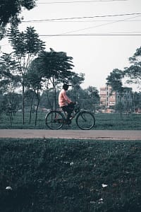 man in white t-shirt riding bicycle on road during daytime
